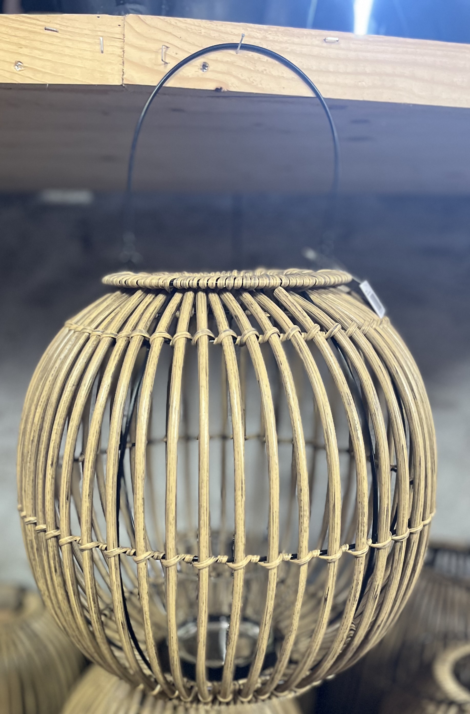 Lykta D35 rund korglykta med svart metallhandtag, hängande på en hylla.