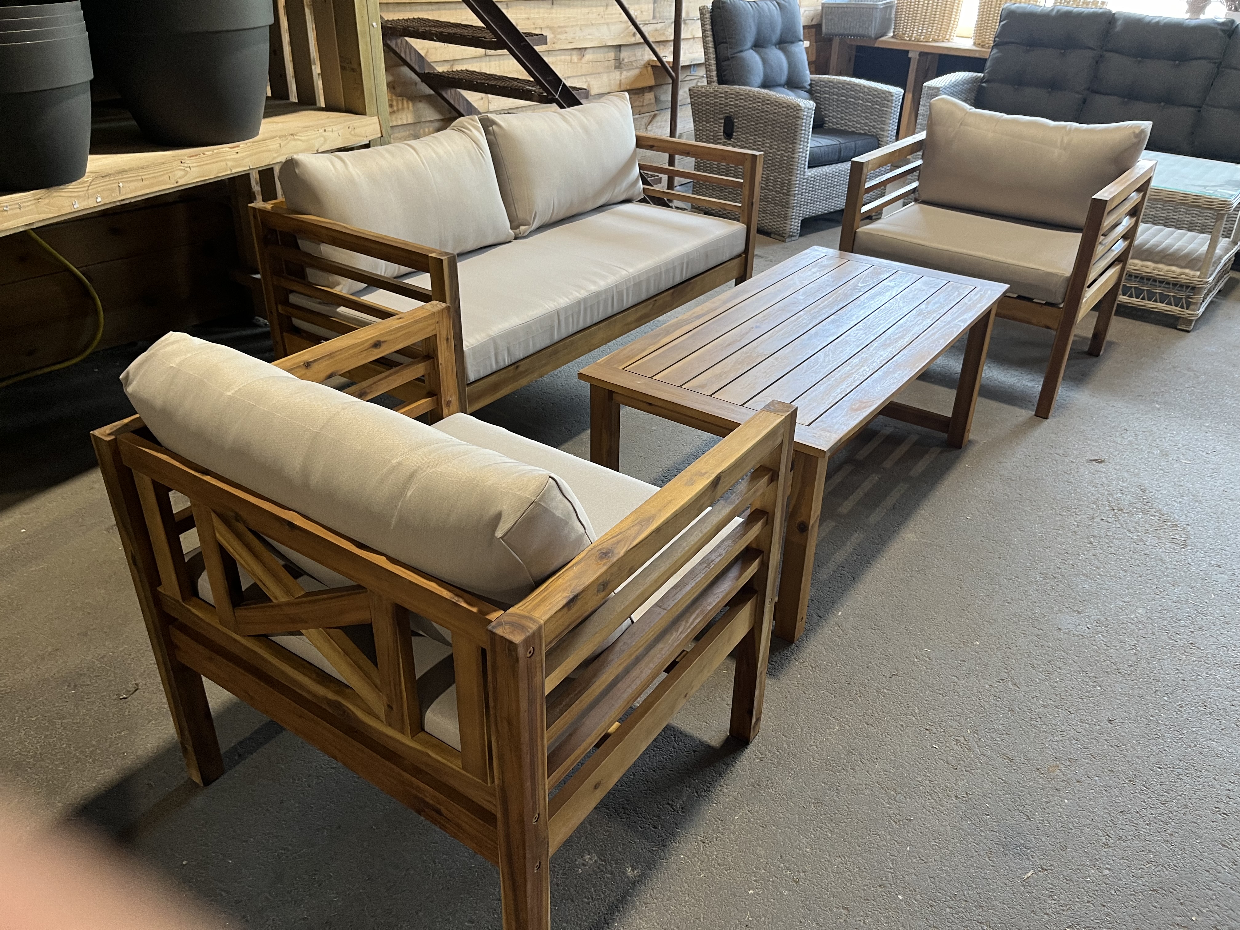 Utemöbel set 4: Uteplats i trä med beige dynor och ett rektangulärt bord inomhus.