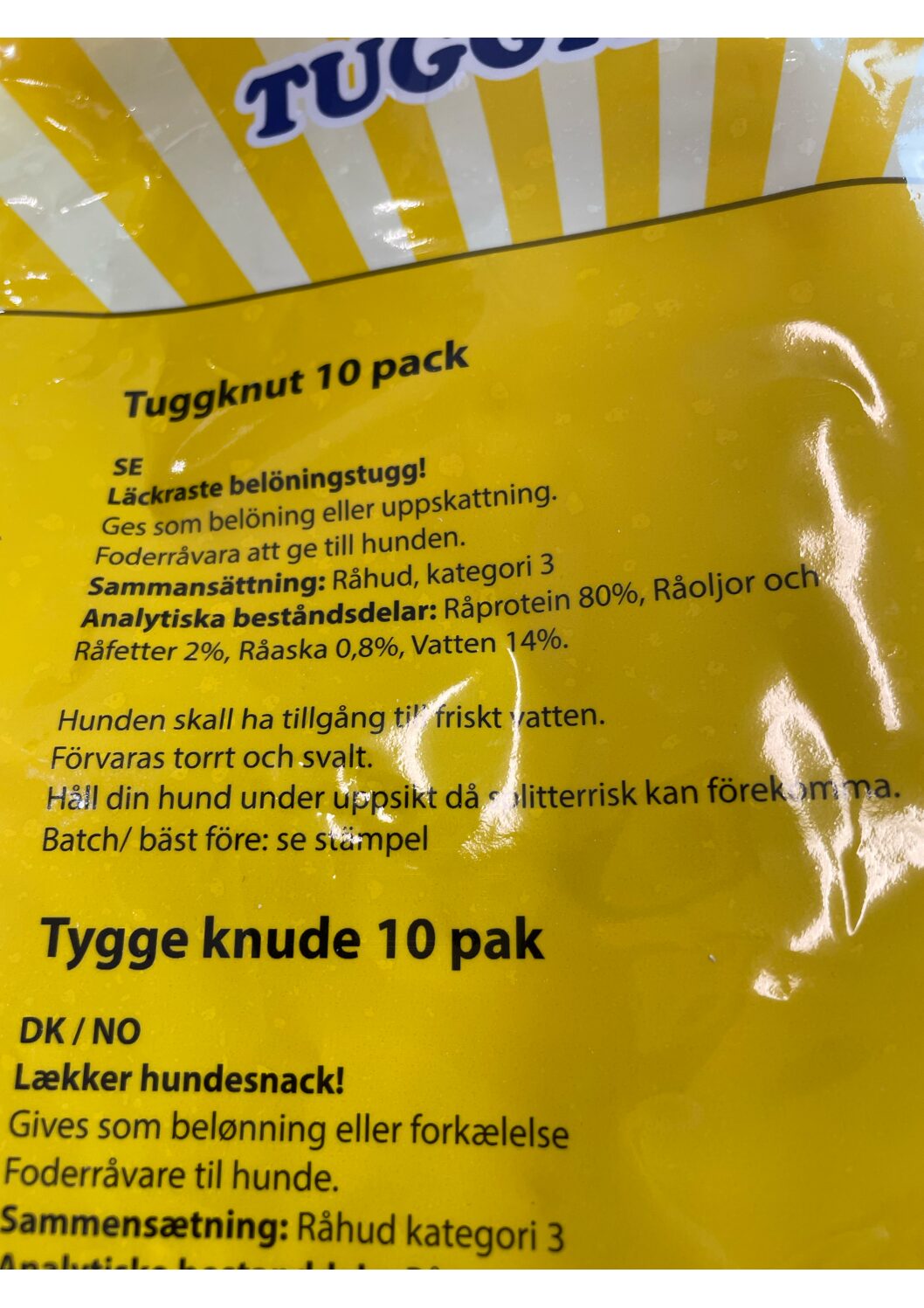 Närbild av gul hundgodisförpackning med text på svenska och danska om ingredienser.