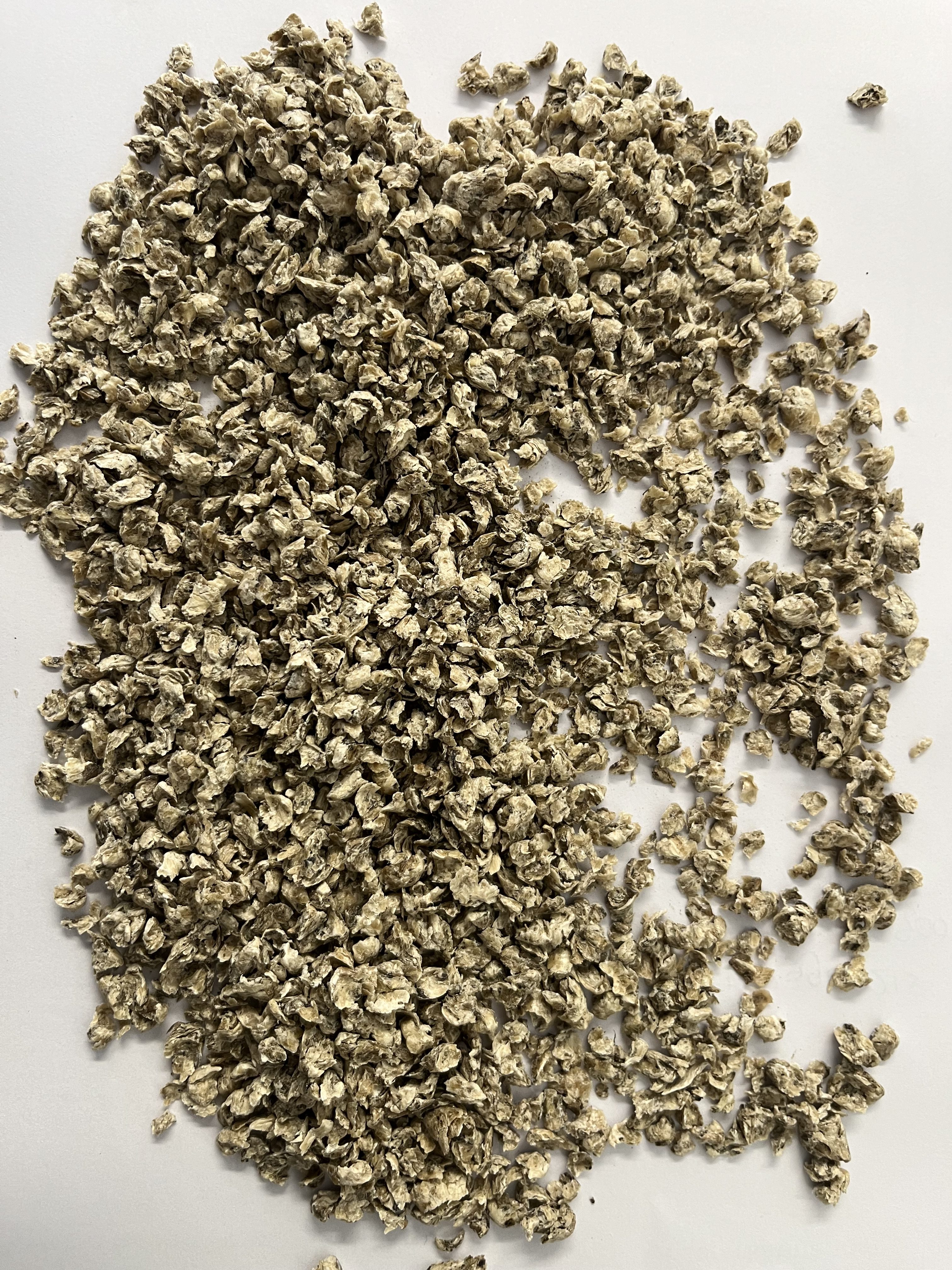 En hög med små, torra, beige havreflingor utspridda på en vit yta.