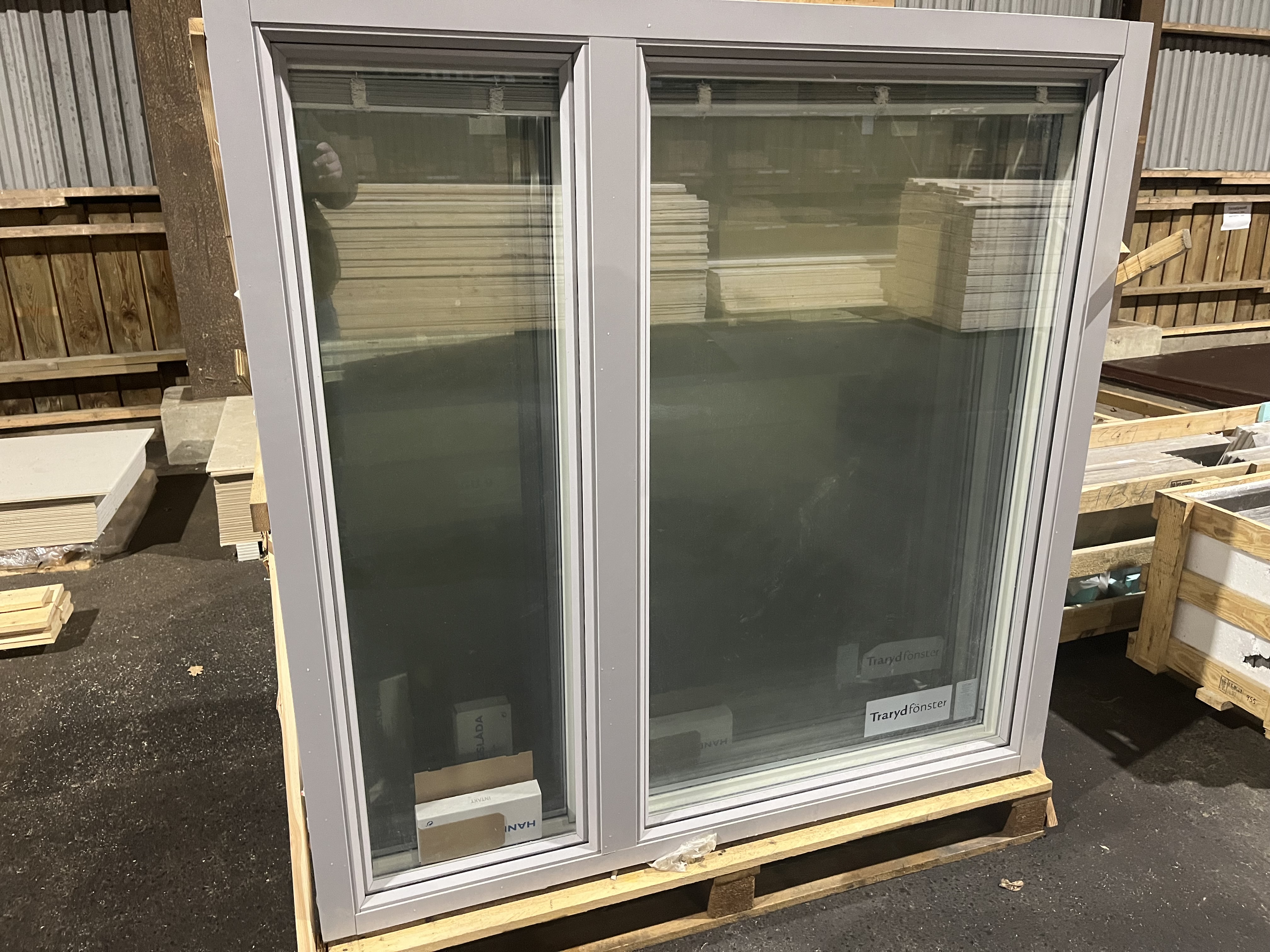 Fönster Traryd 16*16 med grå ram på pall i lagerlokal.