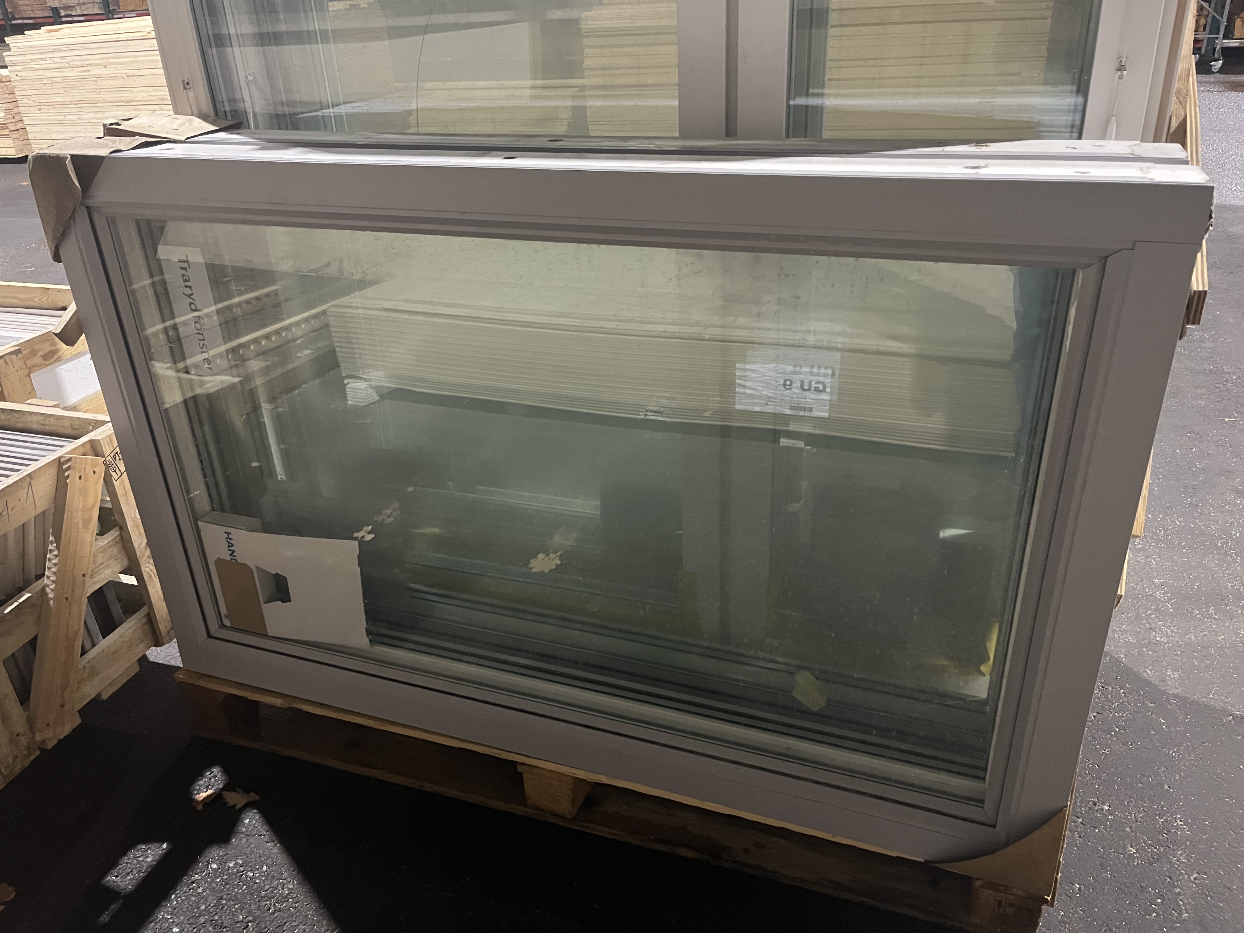 Fönser traryd10*16 med vit ram står på en pall i en lagerlokal.