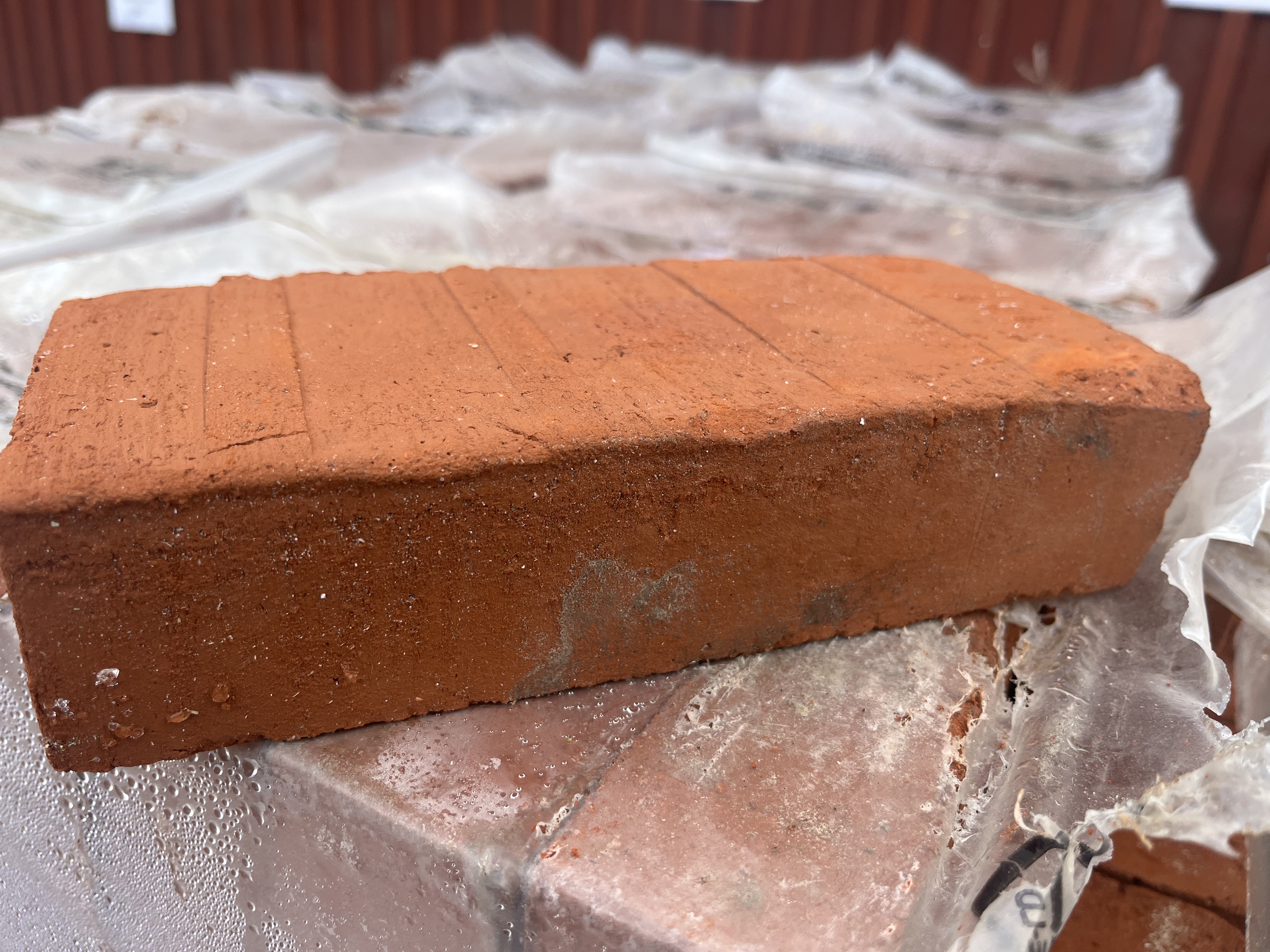 En Tegel RÖD röd tegelsten vilar på en hög med täckta tegelstenar.