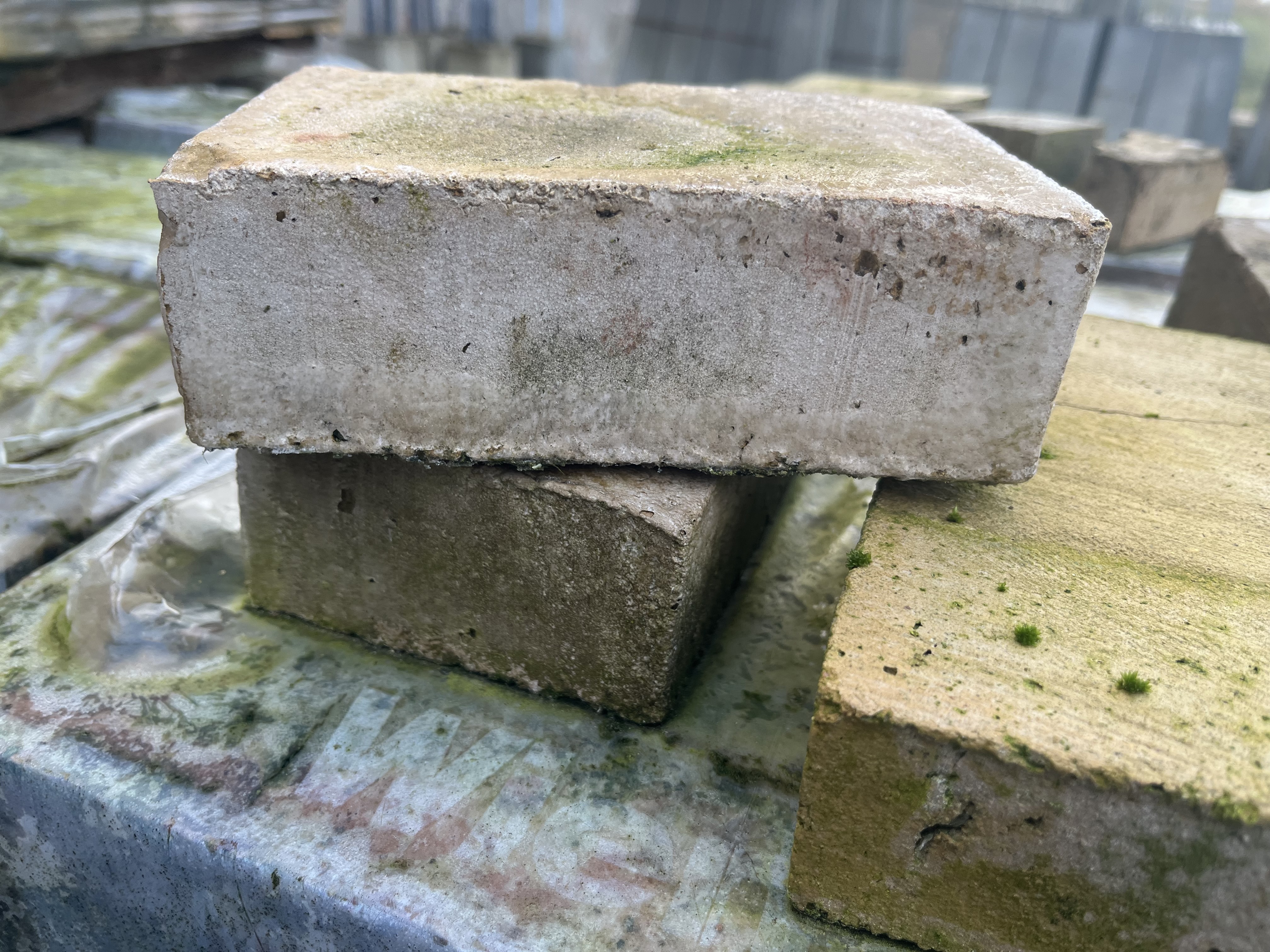 Tre Tegelstenar staplade på en mossig grön yta utomhus.