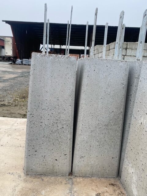 Tre Plint fasta järn 100*500 plattor med metallstänger staplade utanför en industribyggnad.