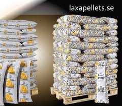 Säckar med Laxa Pellets staplade på pallar med laxapellets.se i bakgrunden.