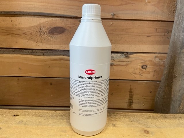 En 1L flaska Mineralprimer på en träyta med en bakgrund av en trävägg.