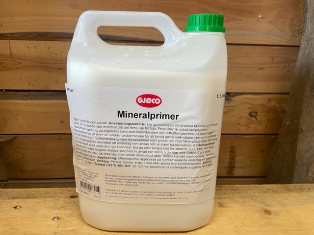En 5L Mineralprimerbehållare med vit stomme och grönt lock på en träyta.