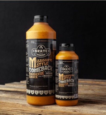 Två flaskor Mississippi Comeback Sauce på ett träbord med mörk bakgrund.