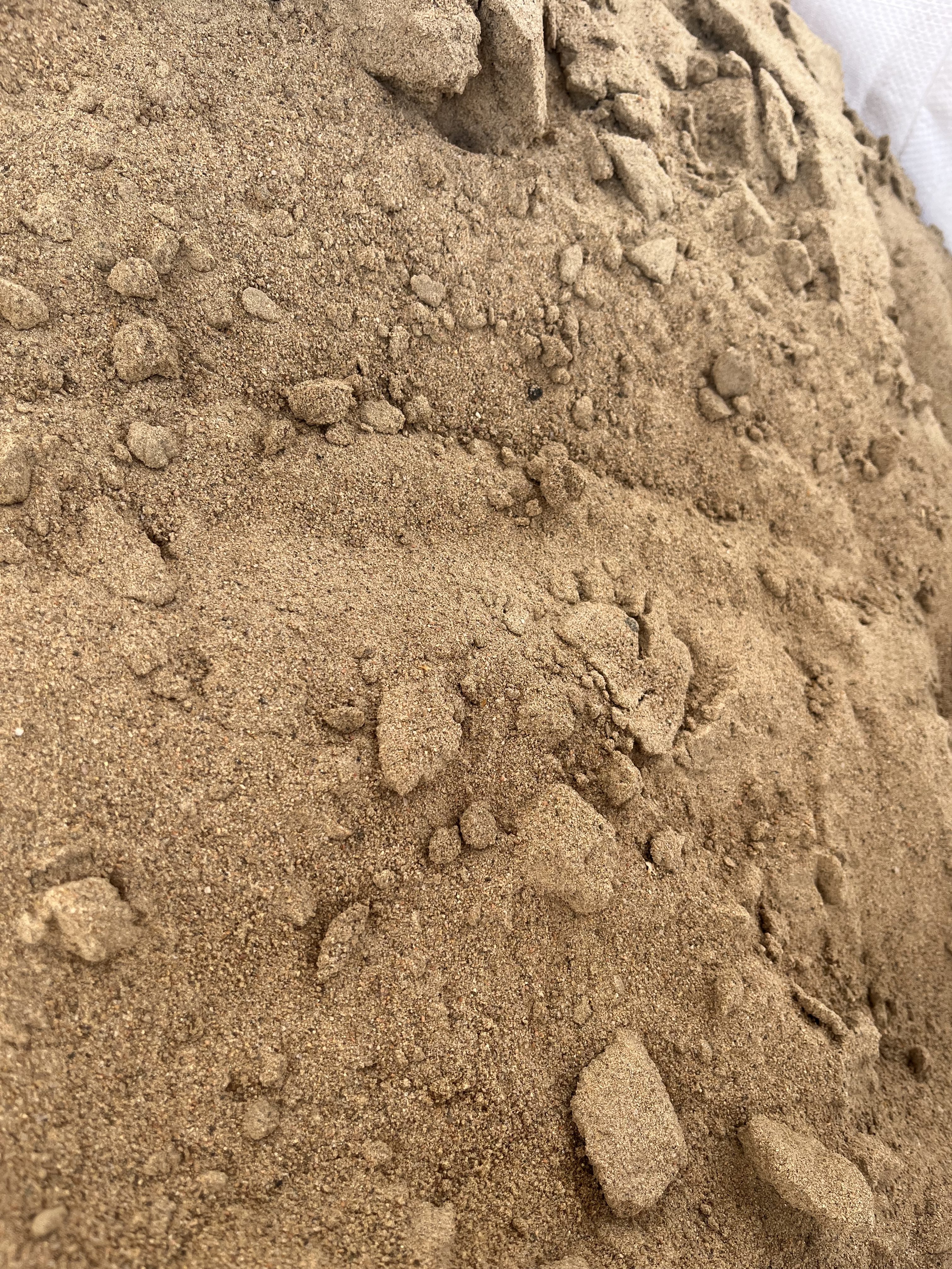 Närbild av Bigbag Murgrus 0-4, ca 600kg: lös, ljusbrun sand med små klumpar och småsten.