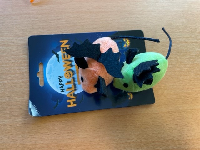 Möss i plysch grön/orange 2-pack med fladdermusvingar på ett Happy Halloween-kort på trä.