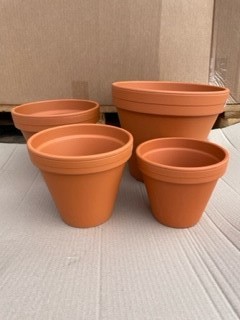 Fyra terrakottakrukor av märket Lerkruka 15 cm Rödlera på en yta av papp.