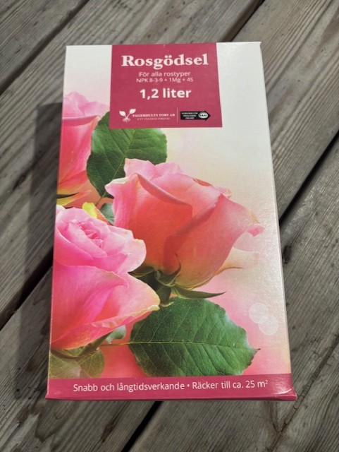 KRAV Rosgödsel 7-2-9 1,2L med rosa rosor på asken, ställd på träplankor.
