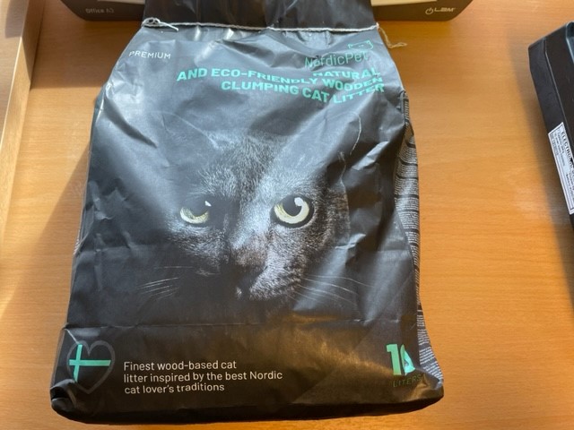 Svart väska av Halmeko nordicPet Kattsand 10L med ett kattansikte i närbild och grön text på framsidan.