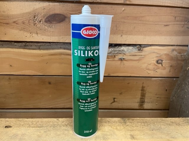 Ett Bygg och sanitärsilikon genomskinligt 310ml rör på trä med en träväggsbakgrund.