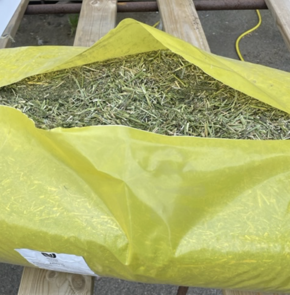 En HALMEKO Hackad lucern 15 kg påse står på en träyta.