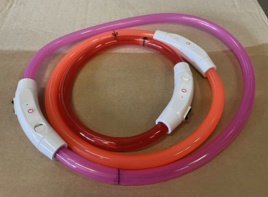 Två färgglada, cirkulära Led halsband, ett rött och ett rosa, med vita kontrollbrytare.