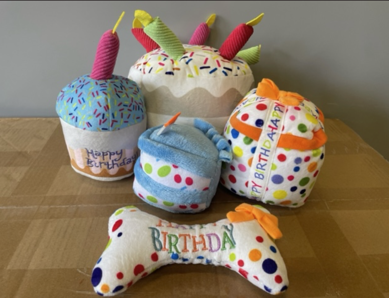 Happy birthday leksaker - Stor tårta: Hundleksaker i plysch med tårta, present och ben på en pappkartong.