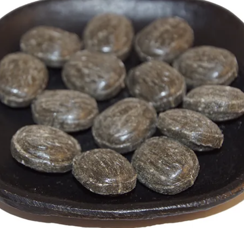 En svart tallrik med flera bitar av lakritsgodiset SALT-LAKRITS AROM "TURKISK PEPPAR".