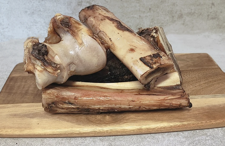 Älgben 4 delar (2knotor, 2rörben) staplade på en skärbräda av trä.