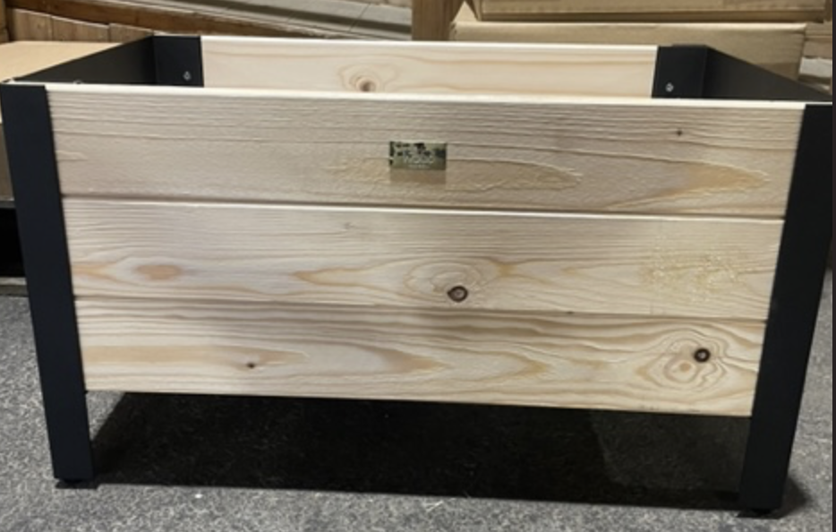 Modernbox L58 H32: rektangulär planteringskärl i trä med svarta metallben på betonggolv.
