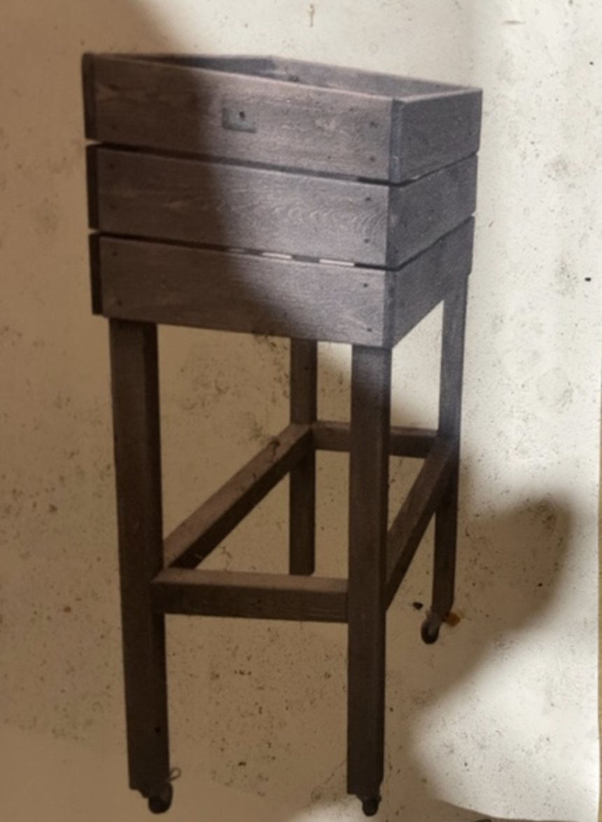 Planteringslåda H93,5 grå på ben med hjul står mot en ljus vägg.