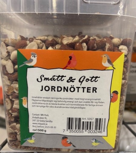 En plastbehållare märkt jordnötter 1,5kg HINK med jordnötter och färgglada fåglar på.