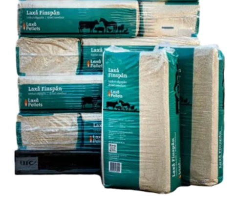 Staplade gröna och beige påsar med Laxå FINSPÅN pellets för djurbäddar.