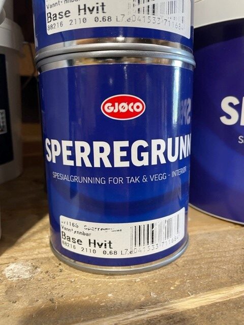 En burk Sperregrunn 0,68LITER står på en trähylla.