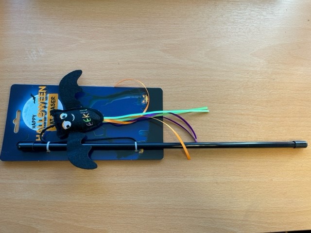 Kattspö med fladdermus och band på en träyta.