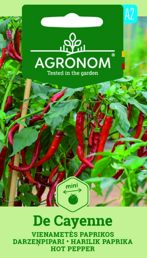 En planta med många långa, röda De Cayenne-paprikor och etiketten på fröförpackningen.