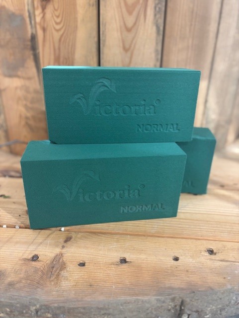 Tre Oasis blomsterskum grönblommiga foamklossar på en träyta.