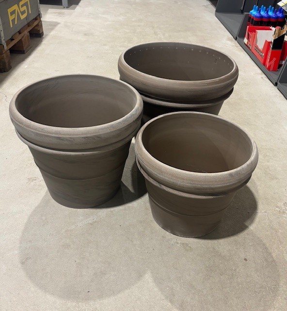 Tre stora tomma bruna växtkrukor av märket KRUKA BASALT på ett butiksgolv av betong.