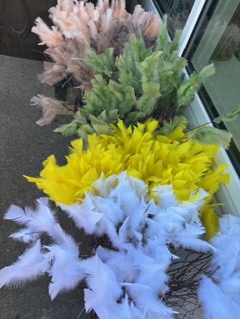 Fjäderris Kalkon: pastellfärgade, gula, gröna och vita fjäderbuntar arrangerade på marken.