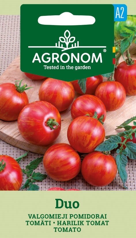 Duo-tomater med röda ränder på en bräda, gröna blad och en Duo-fröförpackning.