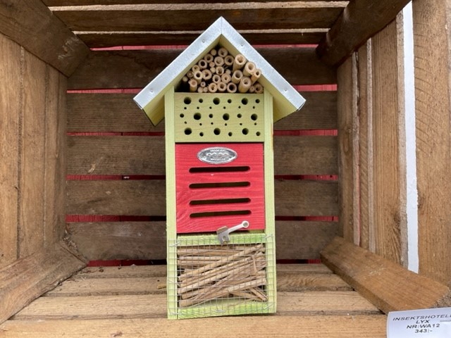 Insektshotell LYX: Grönt och rött insektshus i trä med bamburör i en låda.