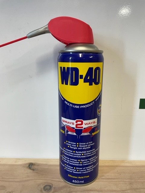 En WD-40 smart straw 450 ml burk med rött munstycke på en träyta.