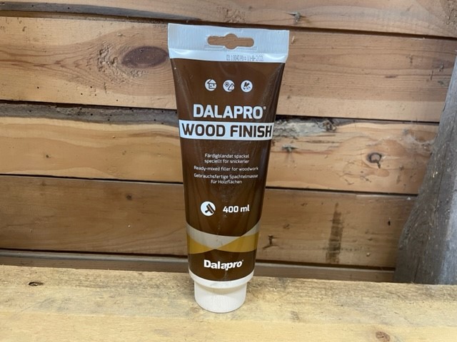 DALAPRO WOOD FINISH 400ML tub på en träyta med en trävägg i bakgrunden.
