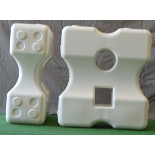 Två Cavalettiblock Large - vit på en grön yta, med geometriska former och fördjupningar.