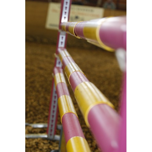 Närbild av en orange FÄRGTILLÄGG BOM-hoppstång på en ridbana.