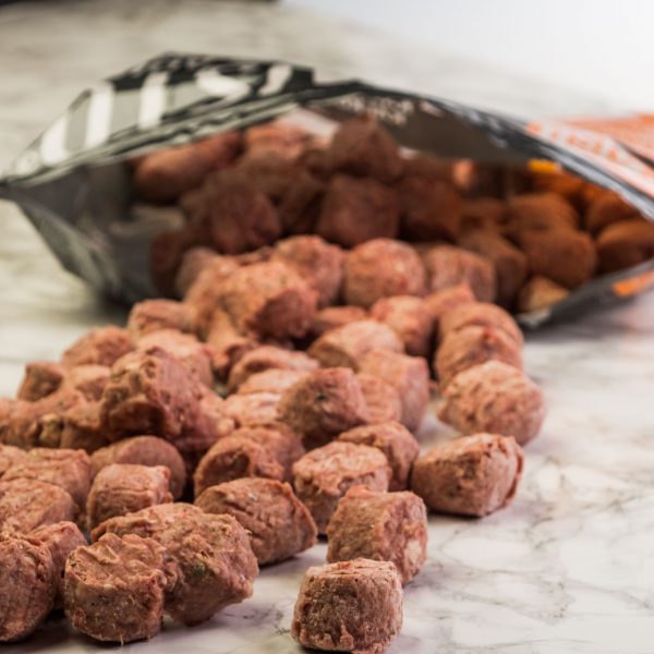 Mush Vaisto Grå frystorkade bitar spills från en öppen påse på en marmoryta.