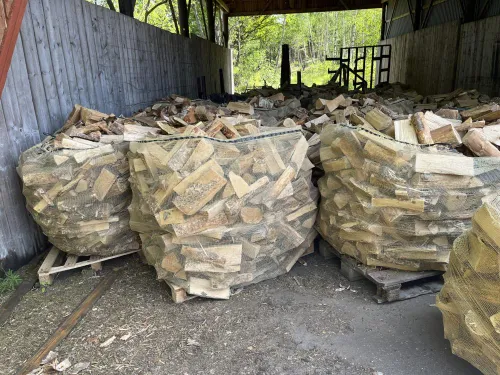 Tre säckar Ved ca 1 kubik blandved är staplade på pallar i ett täckt utrymme.