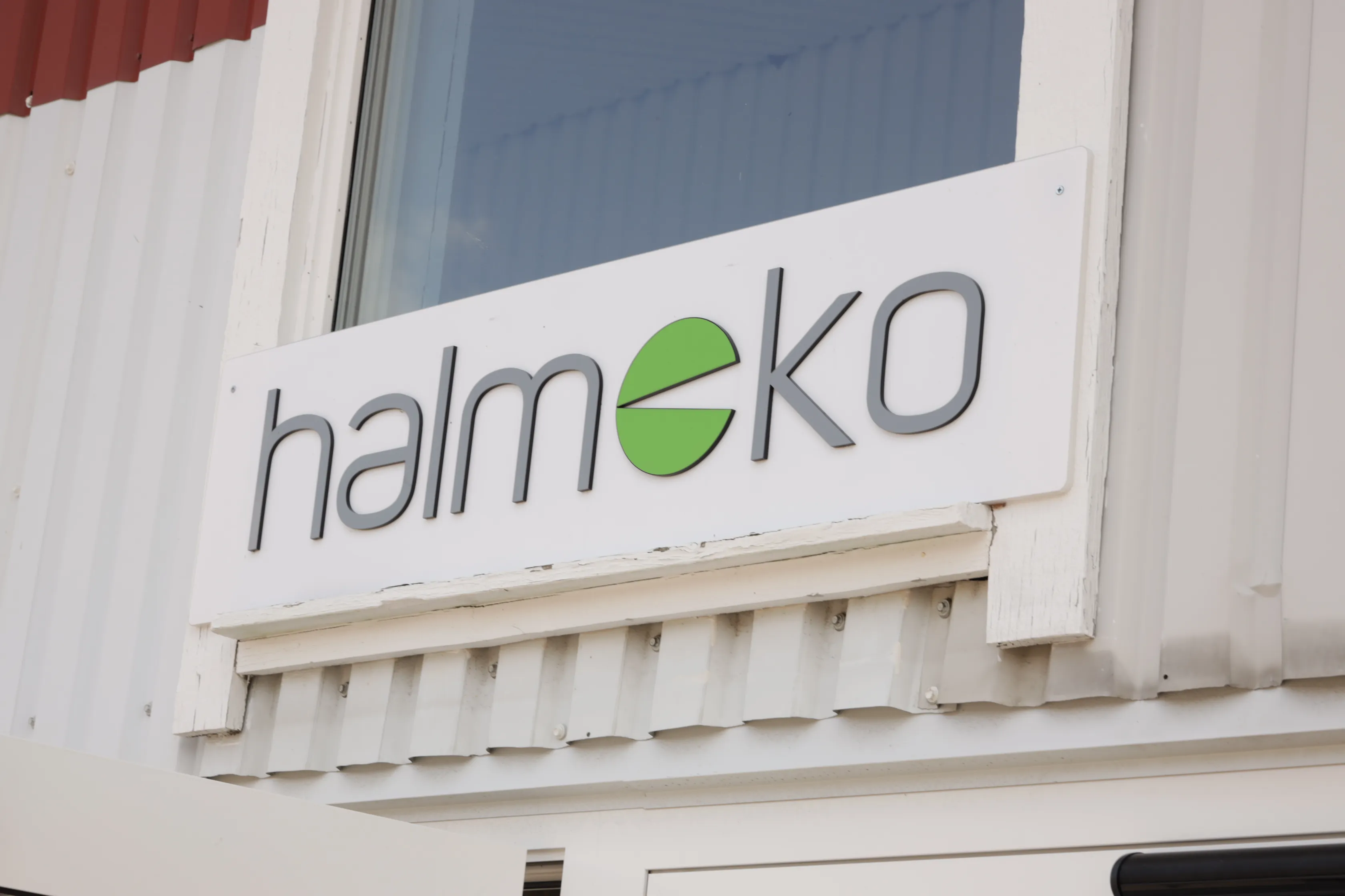En vit skylt med texten halmeko, med bokstaven e stiliserad som en grön cirkel.