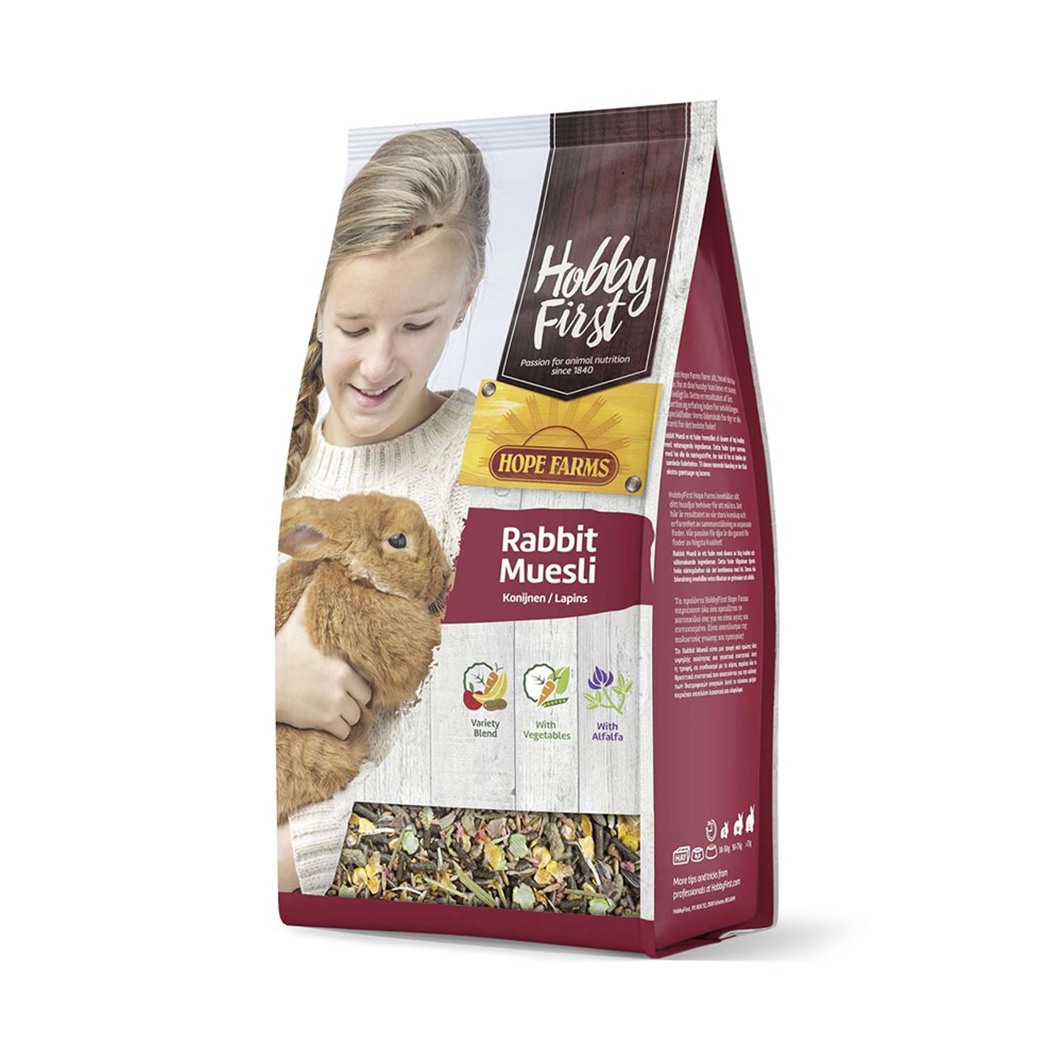 En flicka håller en brun kanin bredvid en påse med Hobby First Rabbit Müsli 2,5 kg.