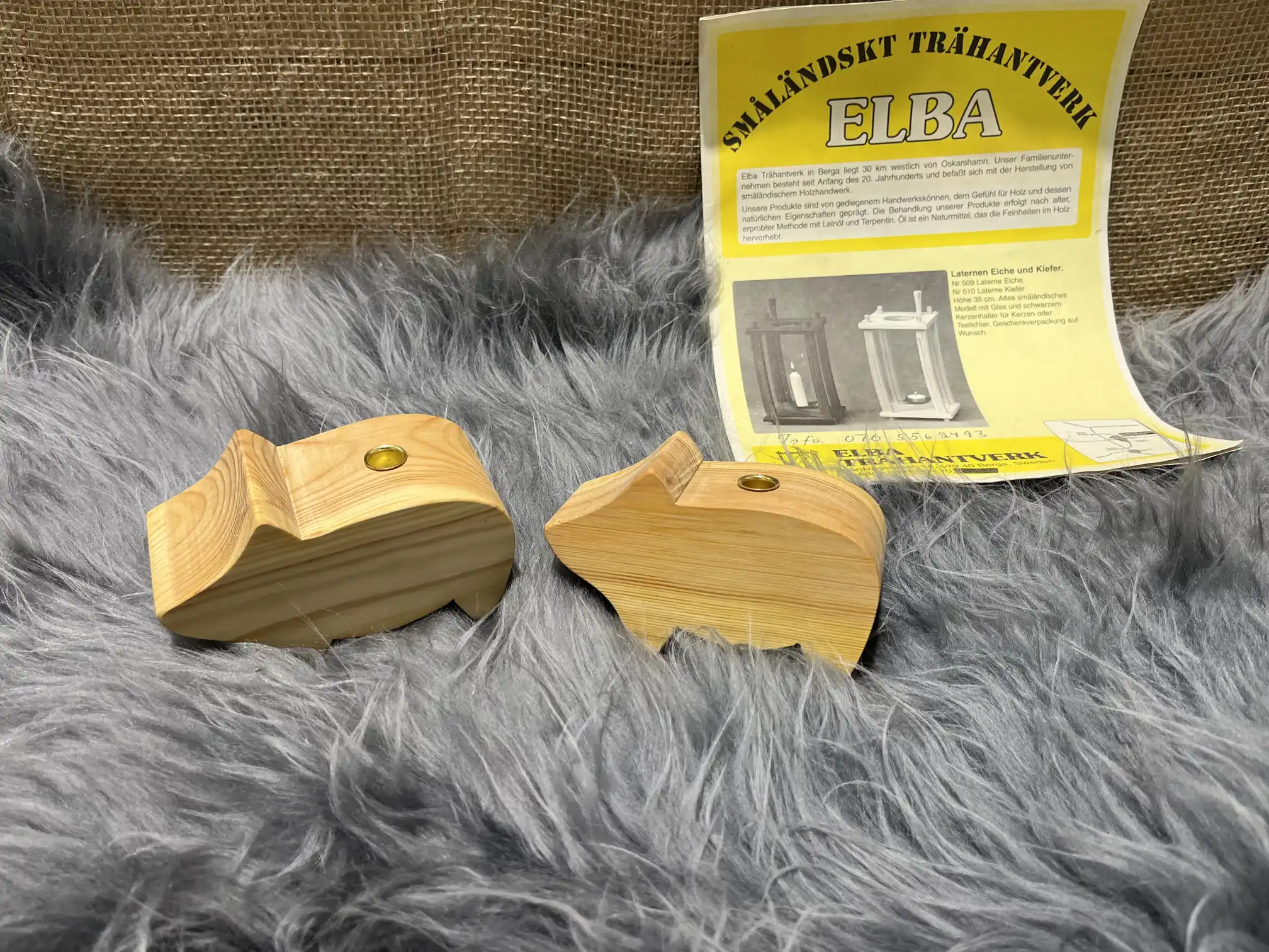 Två Trä gris liten-figurer och ett gult instruktionsblad på en grå luddig yta.