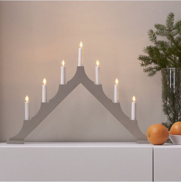 Star Trading Ljusstake Alma, grå 7-ljuskandelaber på vitt skåp med apelsiner och grönska.